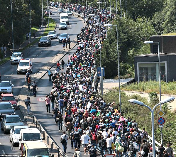 refugees walk beside motorway