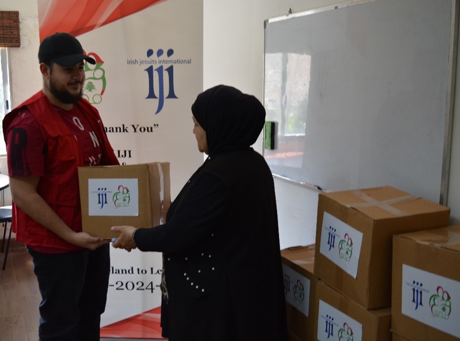 women receives food aid. the box has IJI and MASIR logos on it.