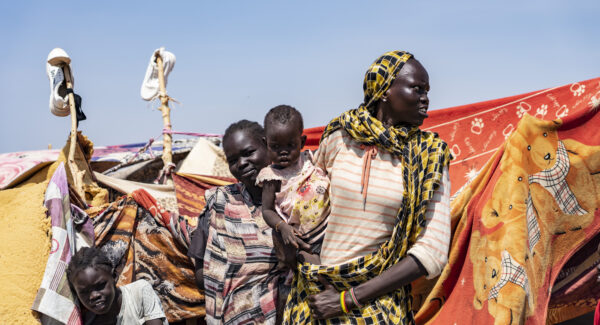 Refugee women hold baby outside their tent in refugee camp in Renk, South Sudan