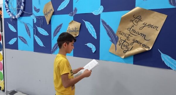 10 year old Moe reads from a page in a JRS education centre in Lebanon.