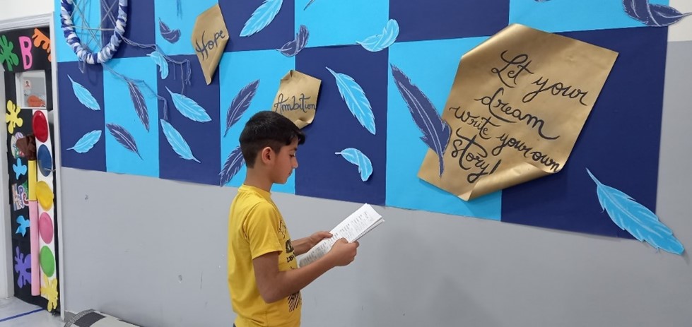 10 year old Moe reads from a page in a JRS education centre in Lebanon.