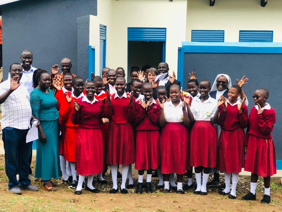 students of St Mary's Assumpta school in Adjumani wave at camera with teachers.