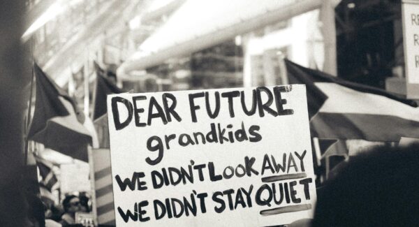 a peaceful Gaza solidarity demonstrator holds sign that reads: "Dear future grandkids, we didn't look away. We didn't stay quiet"