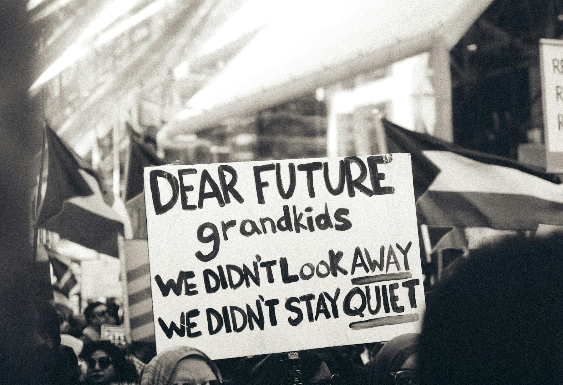 a peaceful Gaza solidarity demonstrator holds sign that reads: "Dear future grandkids, we didn't look away. We didn't stay quiet"