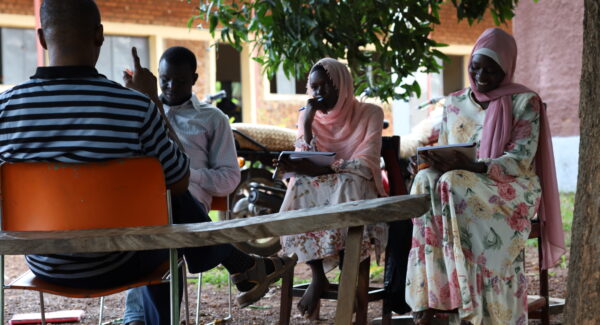 adults take literacy classes under the shade of a tree in South Sudan.